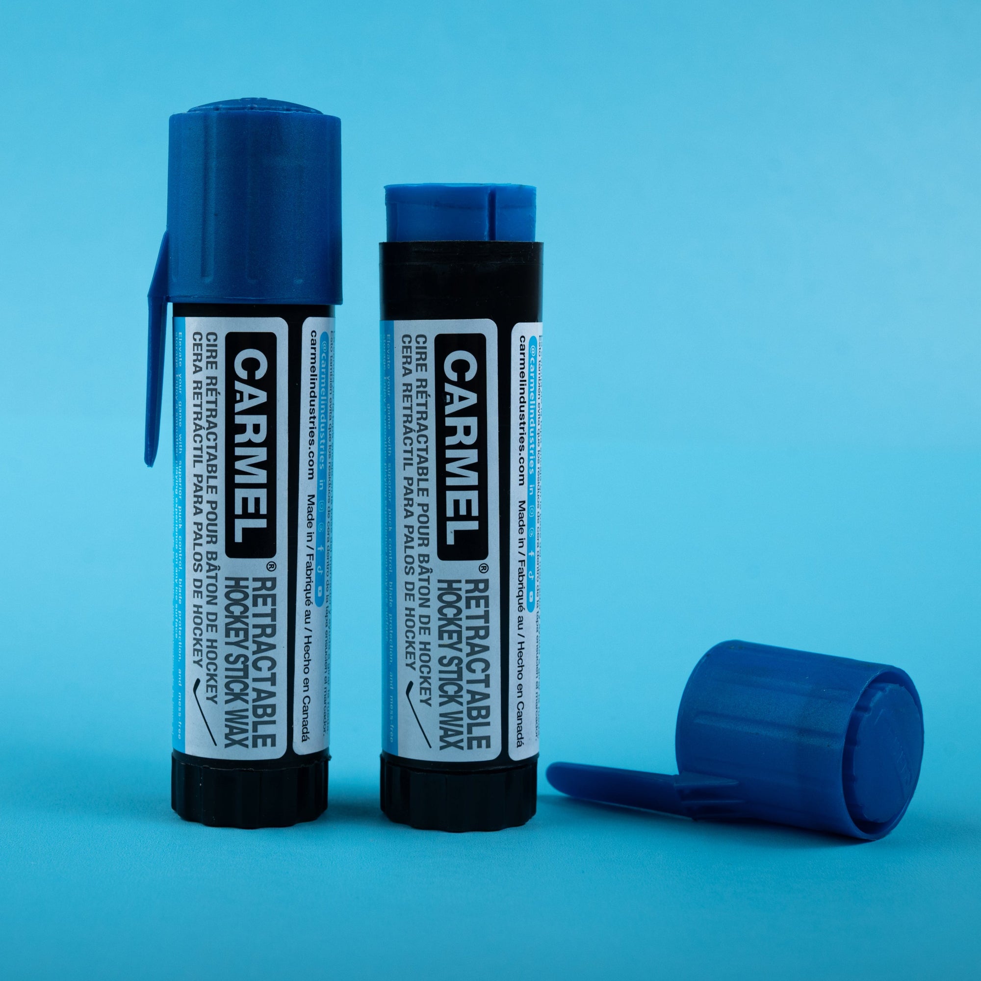 Two sticks of carmel retractable hockey stick wax on a blue background.